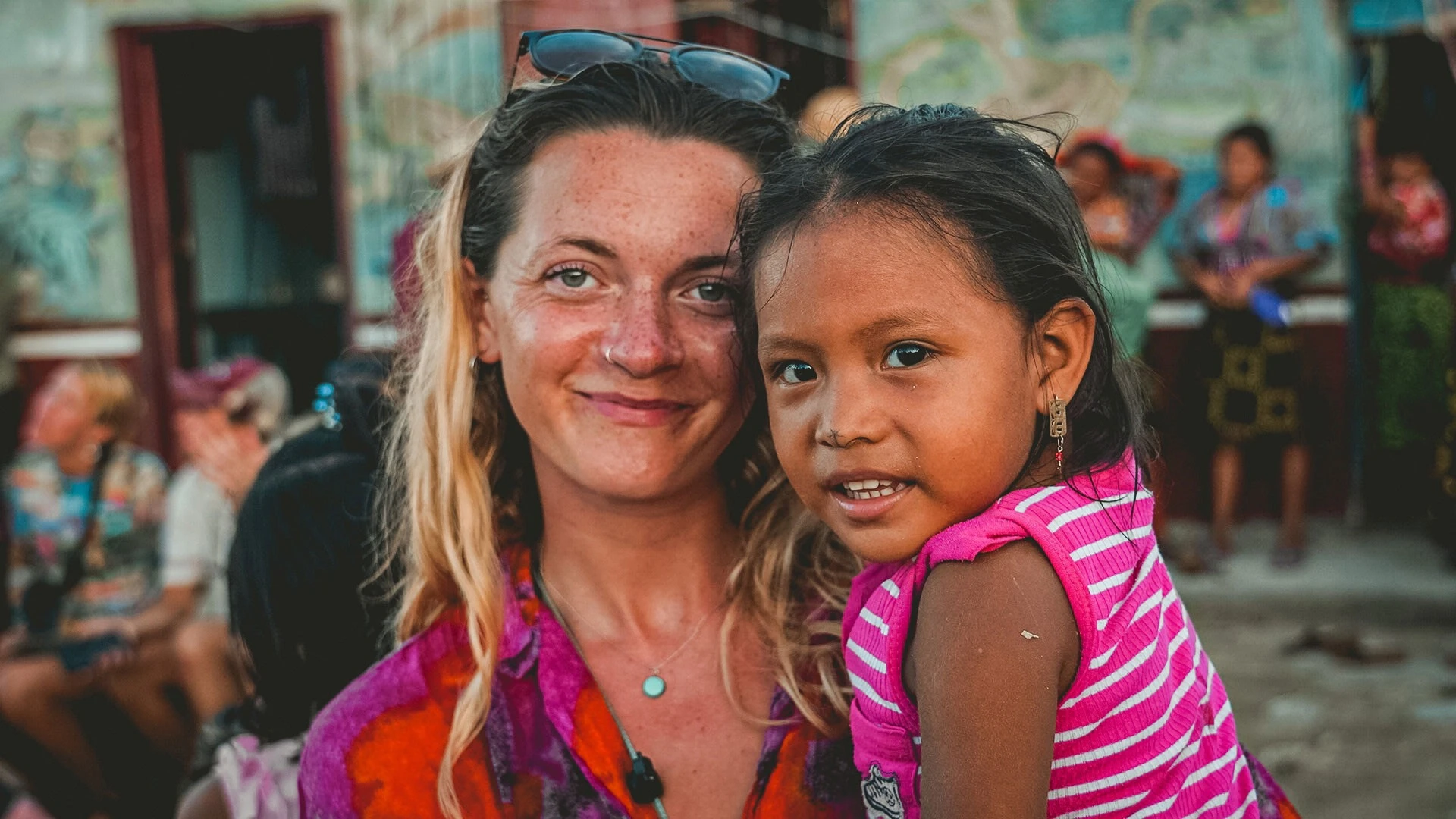 Una viajera y una niña guna sonriendo juntas en una comunidad isleña