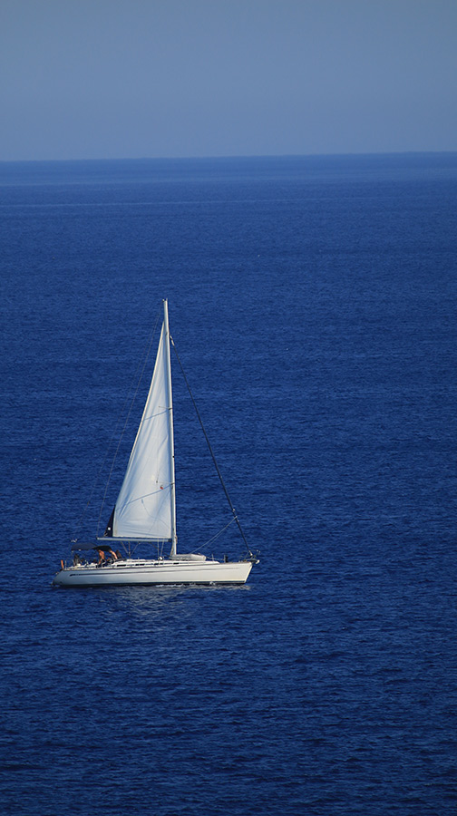White sailboat anchored alone on deep blue open Caribbean sea
